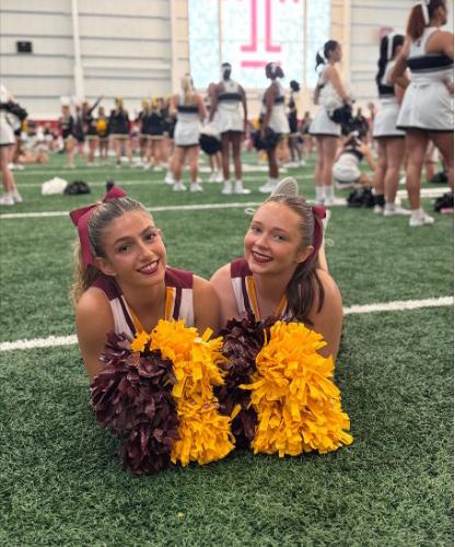 Two Iona Cheerleading Team members on a field, posing and smiling for a photo.