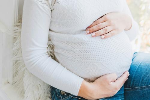 A pregnant woman in a white sweater. Photo by Anastasiia Chepinska.