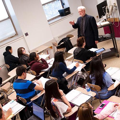 A math professor teaches at the front of class.