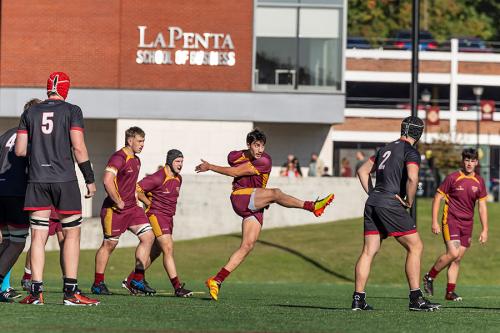 A rugby player kicks the ball down field.