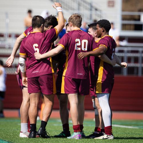 The Rugby Team in a huddle with a raised victory fist.