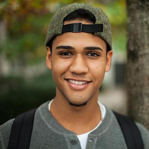 A male student in a backwards cap smiles.