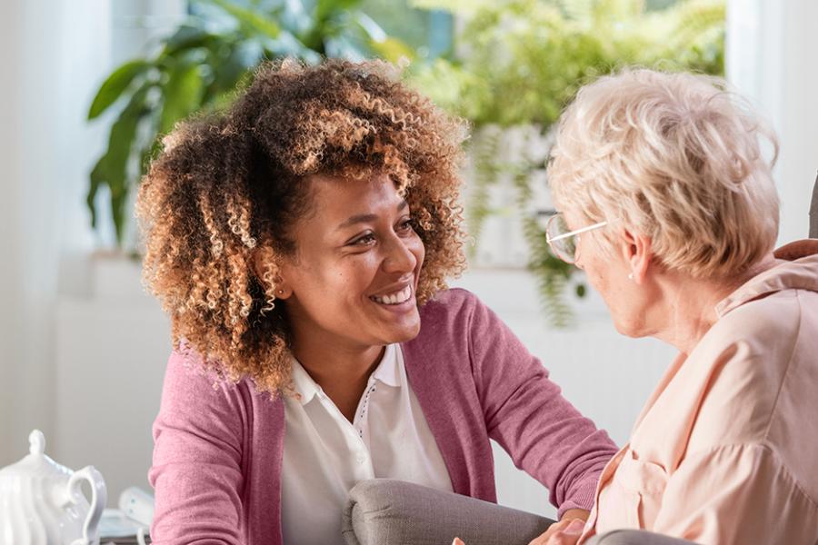 A social worker works with an older client and smiles.