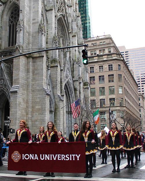 The Irish Dance Team holds the Iona University banner at the St. Patrick's Day parade.