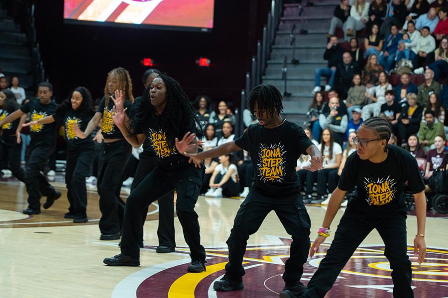 The Step Team performs lined up in a row at a basketball game.