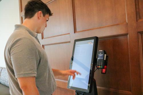 A student orders food at a kiosk in the dining hall.