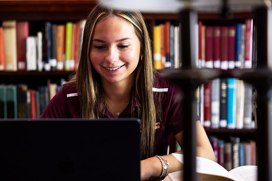 A student with her laptop on a Zoom call in the library.
