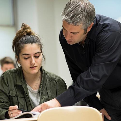 A math professor helps a student in class.
