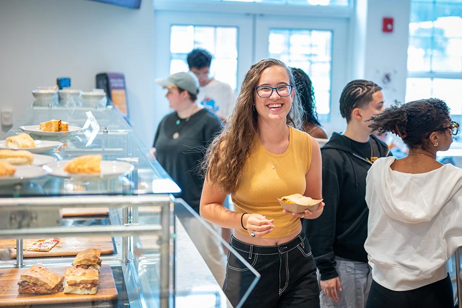 A student leaves the pizza station smiling.