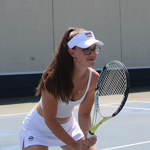 A student on court in a tennis stance.