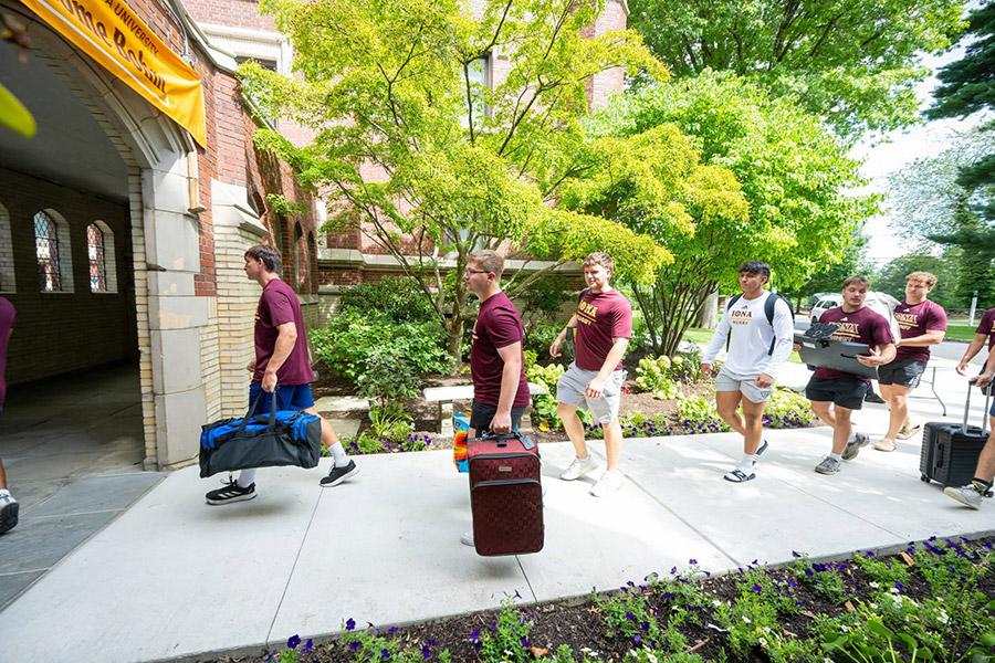 Student athletes help carry luggage into Bohm Hall.