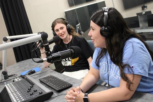 Two students work in the podcast studio.