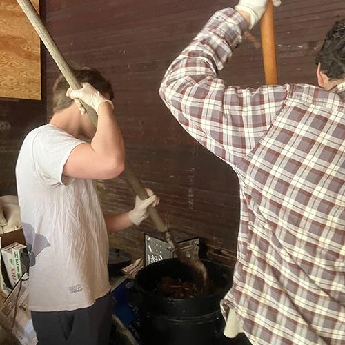 Two students help with shoveling compost.