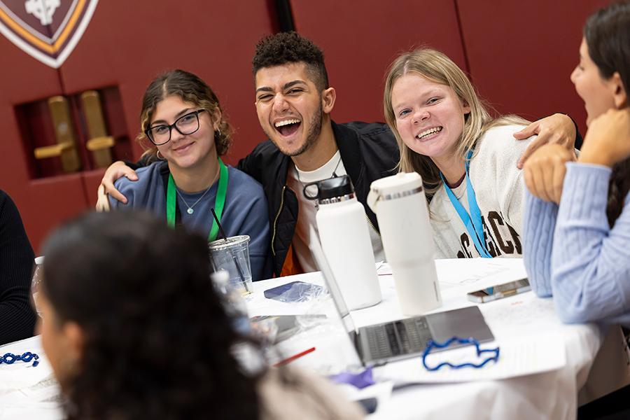 Students smile together at a table in Mulcahy.