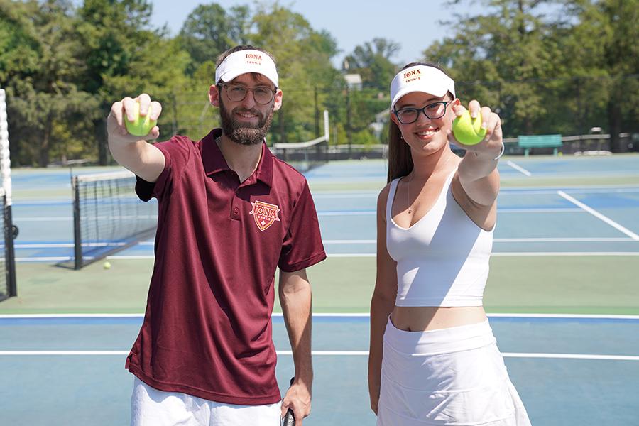 Two students hold out tennis balls on the tennis courts.