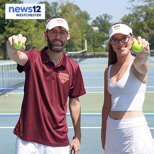 Two students hold out tennis balls on the tennis courts with the News12 logo.