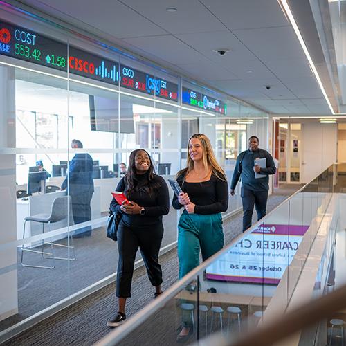 MBA students walk past the trading floor in the business school.