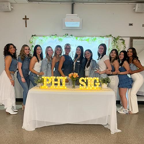 Phi Sigma Sigma at a table with Phi Sig decorations.