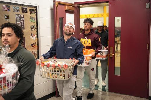 Students bring Thanksgiving baskets out of the gym.