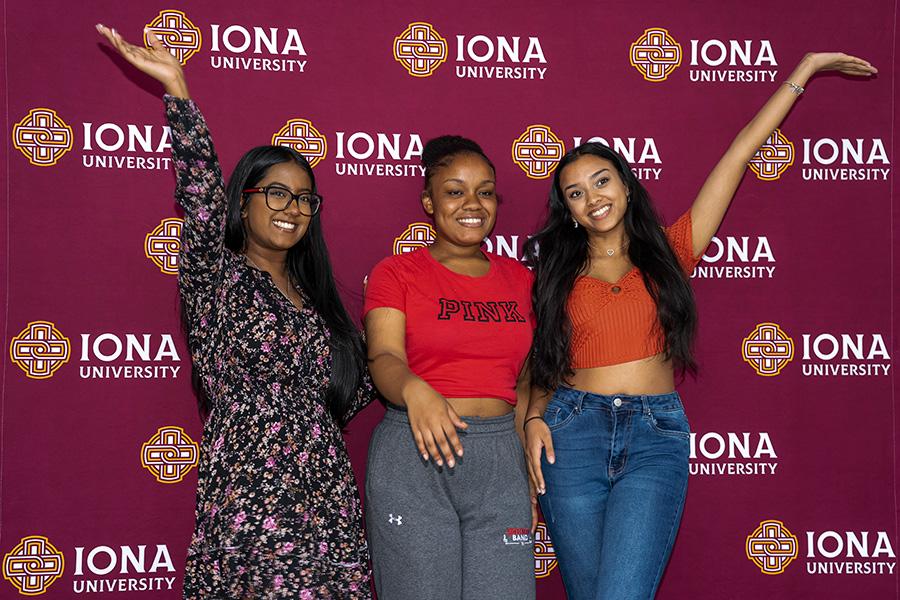 Three students smile and raise their arms at a step and repeat.