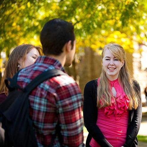 Students on campus talk on a sunny day.