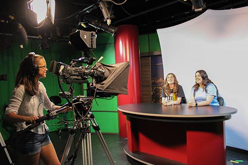 Three students film in the TV studio.