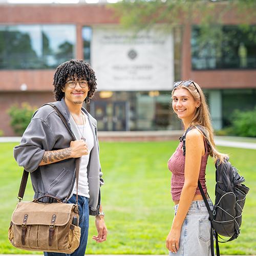 Two students smile in front of the Kelly Center for Health Sciences.