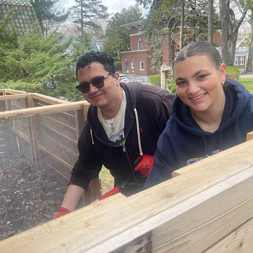 Two students smile as they compost.