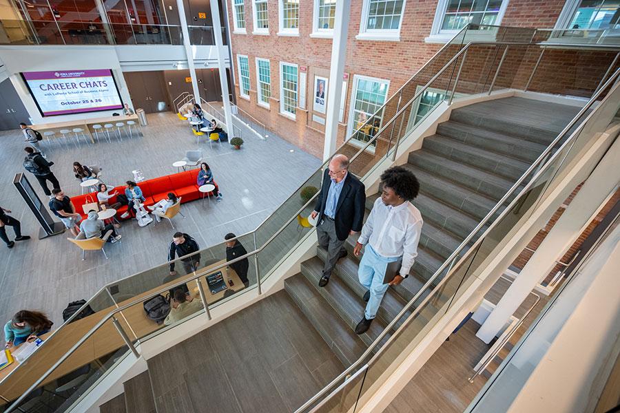 Student and teacher walking down staircase in LaPenta School of Business