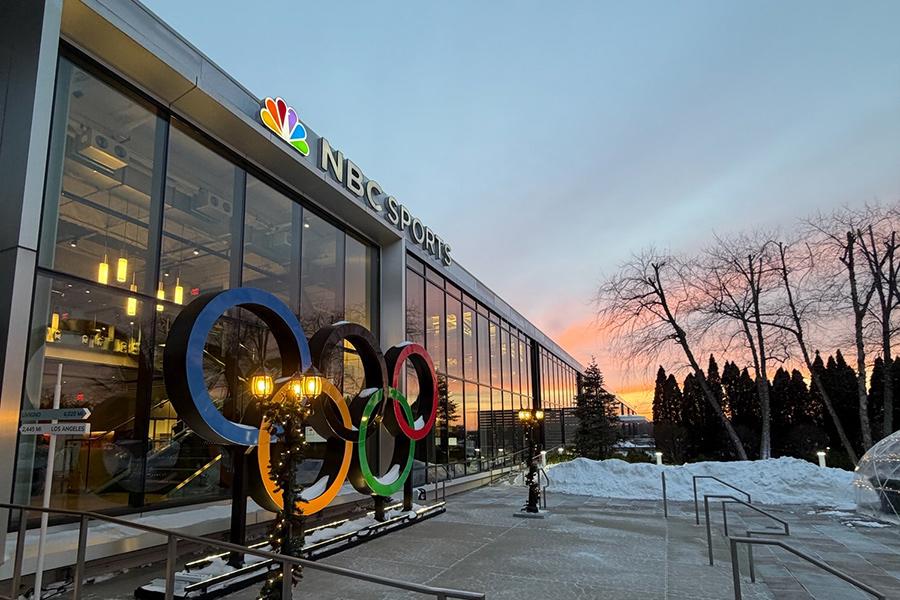 The front exterior of the NBC Sports building as the sun is setting in the background.
