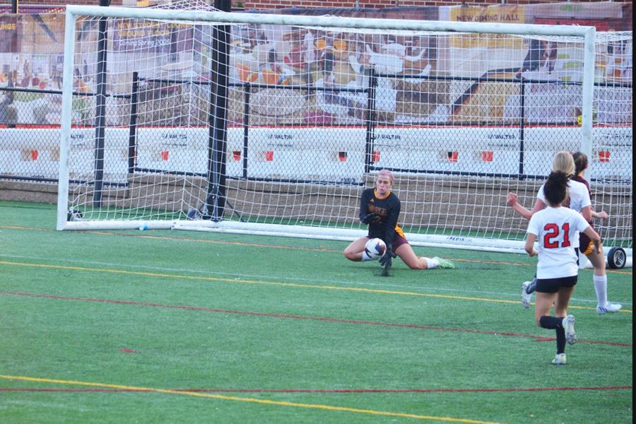 The women's club soccer goalie defends a goal.