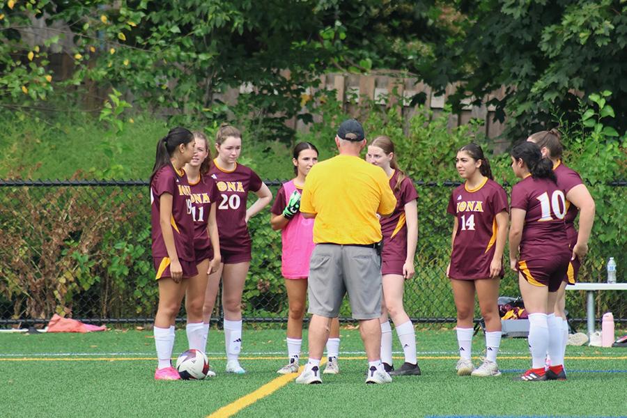 The women's club soccer team huddle up with their coach.